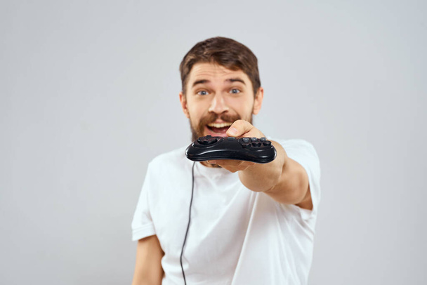 Muž s joystick v ruce zábavné hry životní styl bílé tričko lehké pozadí - Fotografie, Obrázek