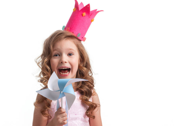 Beautiful little candy princess girl in crown holding pinwheel and smiling - Фото, зображення