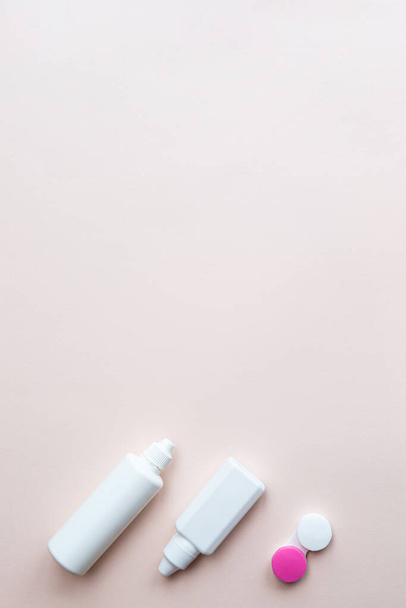 Contact lenses, lens solution and lens containers on a light pink background. Health care concept top view copy space - Fotó, kép