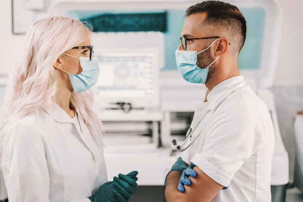 Deux assistants de laboratoire dédiés se tenant en laboratoire et parlant d'un nouveau remède contre le virus de la couronne. - Photo, image