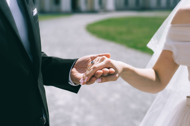 Close up of wedding couple holding hands outdoors. Blurred background. - 写真・画像