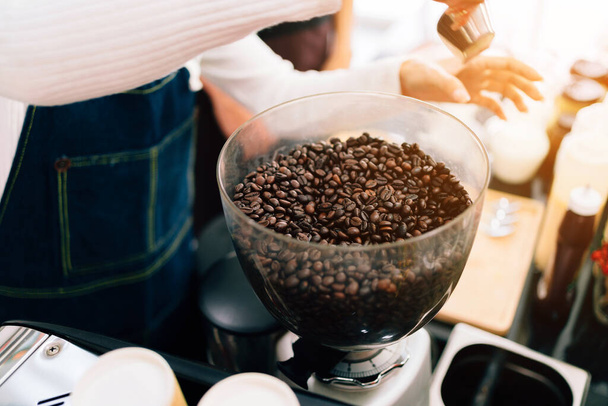 Zbliżenie ziarna kawy wewnątrz elektryczne szlifierki do kawy szlifierki. Młynek do kawy zarówno w gospodarstwie domowym, jak i w biznesie. Zajęcia z przygotowywania kawy dla początkujących przedsiębiorców rozpoczynających działalność gospodarczą. - Zdjęcie, obraz