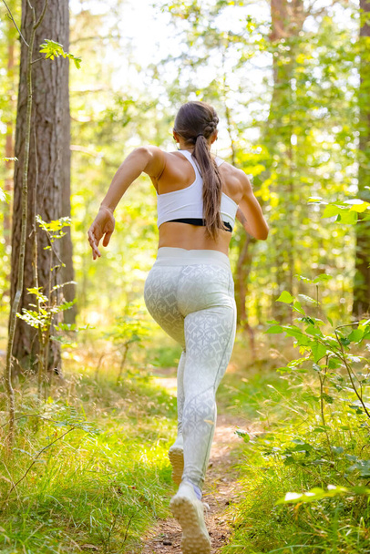 Mujer corriendo en el bosque durante el entrenamiento al aire libre - Foto, Imagen