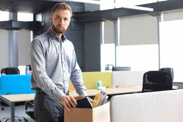 Sad dismissed worker are taking his office supplies with him from office - Photo, image