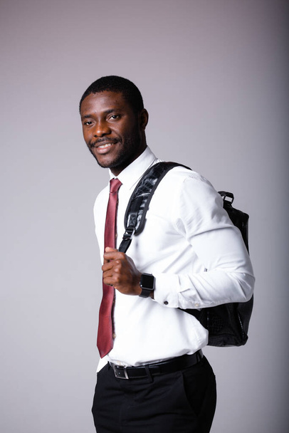 Portrait of an African American man in a white shirt, with a black backpack on his shoulder. Young student - Photo, Image
