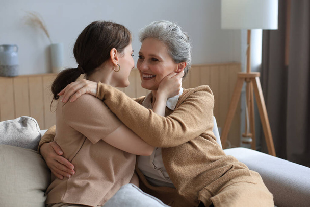 Attractive young woman hugging mature mother, smiling affectionately - Foto, imagen