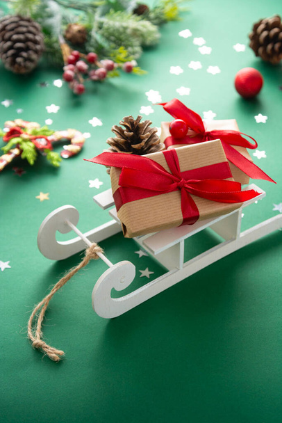 Sleigh with Christmas presents, winter decorations, green background. - Фото, зображення