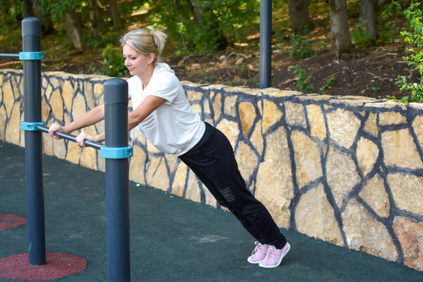 Happy sportswoman on gym outdoor. Woman on a sports trainer on sports ground. - Foto, Bild