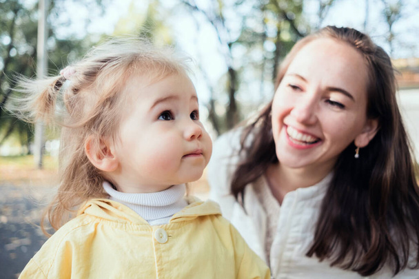 blank kind meisje en moeder portret glimlachen in het park. - Foto, afbeelding