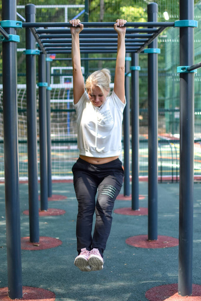 Happy sportswoman on gym outdoor. Woman on a sports trainer on sports ground. - Photo, image
