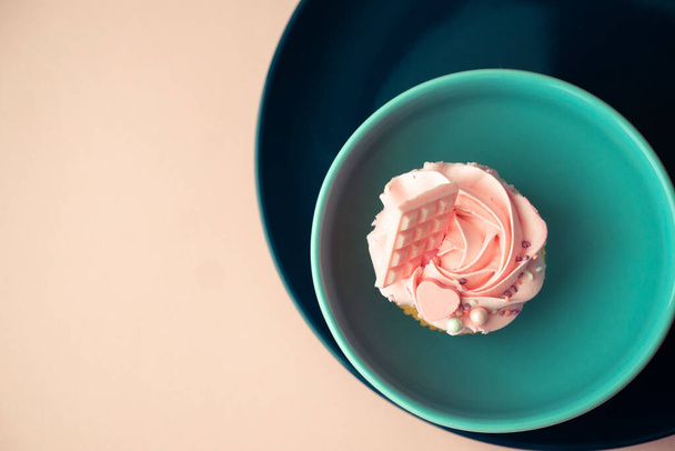 Pink chocolate cupcake with butter cream. Top view of dessert in round plates on a solid surface. - Photo, Image