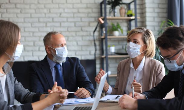 Business people wearing protective face masks while holding a presentation on a meeting during coronavirus epidemic - Foto, Imagem