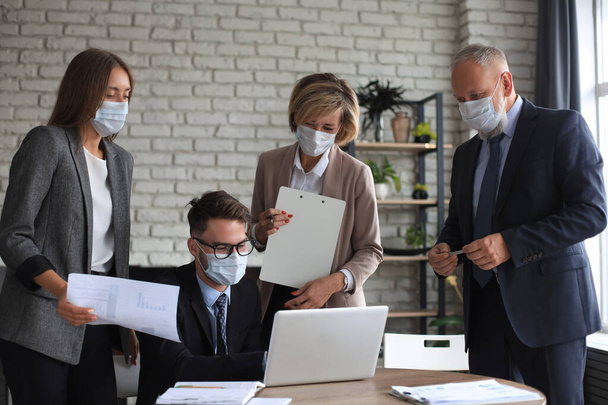 Business people wearing protective face masks while holding a presentation on a meeting during coronavirus epidemic - Photo, Image