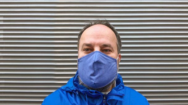 homme d'âge moyen portant un masque facial en tissu ou un masque communautaire pendant la pandémie de corona covid-19 - Photo, image