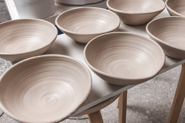 many raw ceramic bowls made from white clay waiting for putting in the pottery kiln. concept of manual work, creativity and art - Foto, Imagem
