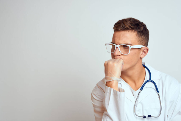 Arzt im Arztkittel mit Stethoskop und Brille auf hellem Hintergrund - Foto, Bild