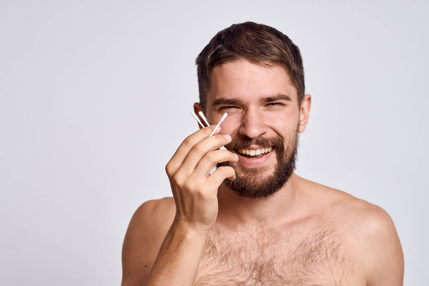 Hombre barbudo con hombros desnudos hisopos de algodón higiene cuidado corporal - Foto, imagen
