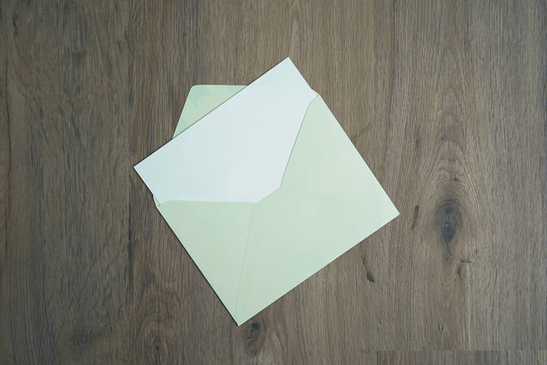An open green envelope on the wood desk, top view. - Photo, Image