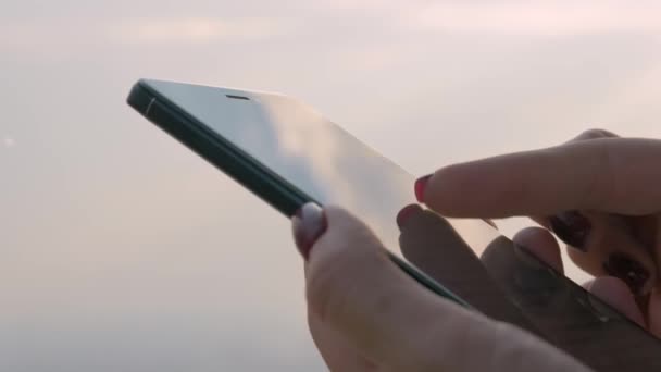 Женщина, использующая смартфон против ясного неба - близкий обзор - Кадры, видео