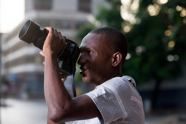 mladý muž stojí venku a dívá se na fotoaparát s úsměvem. - Fotografie, Obrázek