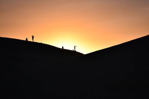 Силуэт нескольких дюн в пустыне на закате. - Фото, изображение