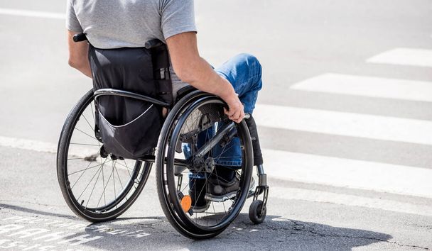 Handicapped man in wheelchair preparing to cross the road on pedestrian crossing - Fotoğraf, Görsel