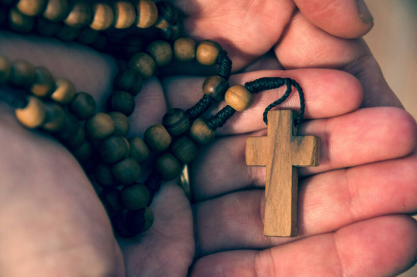 Manos de mujer caucsica ofreciendo Rosario de cruz y cuentas de madera - Photo, Image