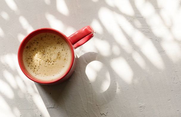 Cappuccino in een rode Beker op een grijze betonnen achtergrond. - Foto, afbeelding