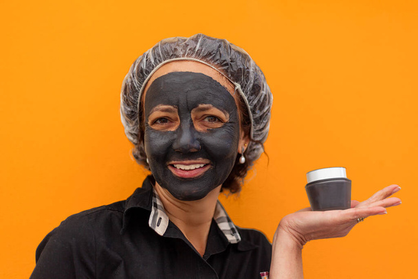 Close up de mulher com máscara de lama segurando um frasco de creme - Foto, Imagem