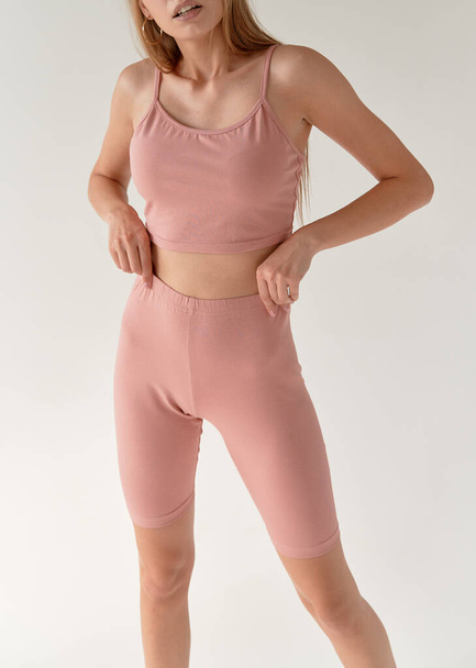 woman wears pink fitness sport costume white studio background. nude color suit for yoga - Photo, image