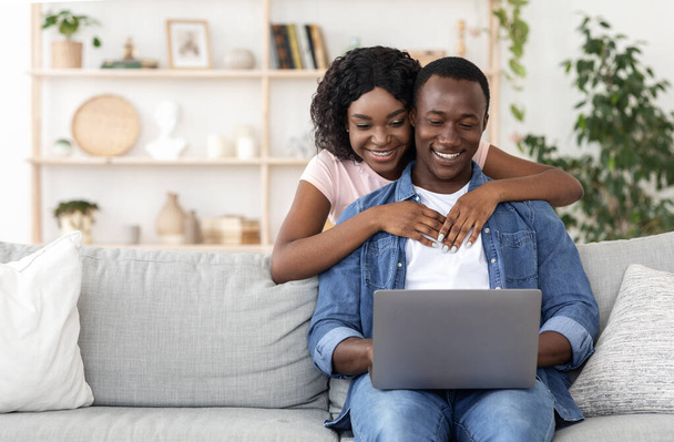 アフリカ系アメリカ人のカップルを愛する家庭で一緒にラップトップを使用して - 写真・画像