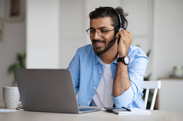 Smiling Young Indian Guy Watching Webinar On Laptop, Wearing Headset And Eyeglasses - Photo, Image