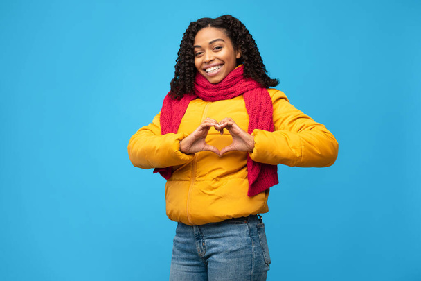 Positivo Afro-Americano Señora Gesturing forma de corazón sobre fondo azul - Foto, imagen