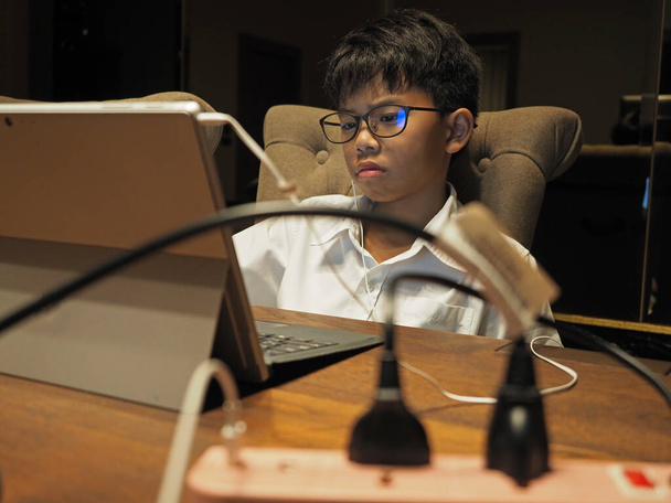 Detailní záběr asijského chlapce, jak doma studuje s vážnou tváří. Vybrané zaměření. - Fotografie, Obrázek