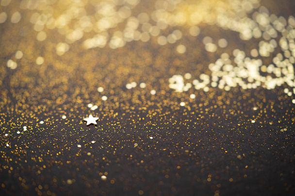Beautiful Christmas light background. Abstract glitter bokeh and scattered sparkles in gold, on black - Foto, Imagen