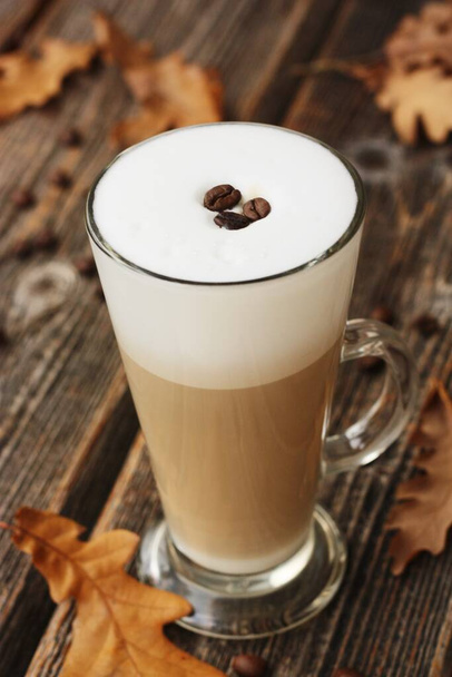 Kávové latté s fazolemi a dubovými listy na stole - Fotografie, Obrázek