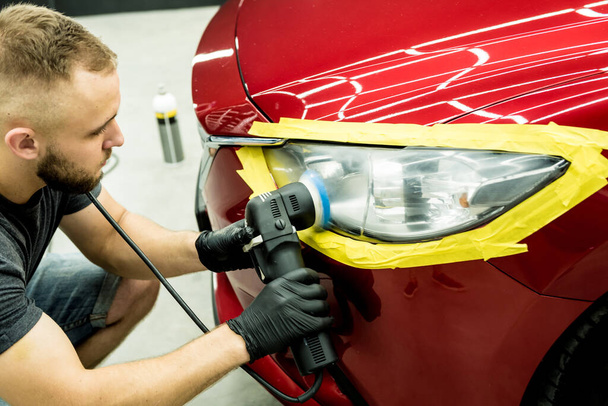 Car service worker polishes a car details with orbital polisher. - Foto, afbeelding