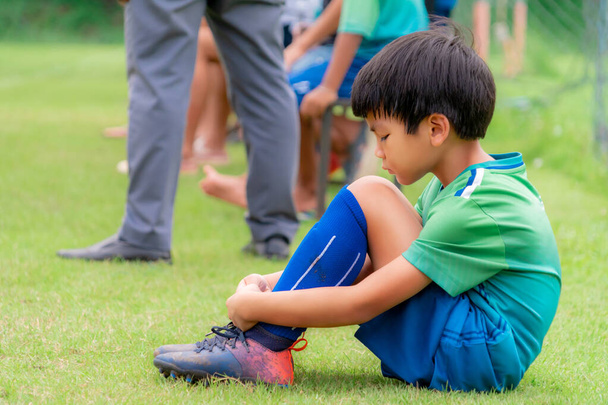 悲しいサッカーの子供はフィールド側の代替ベンチに座っているが、競争の試合でプレーすることはありません - 写真・画像