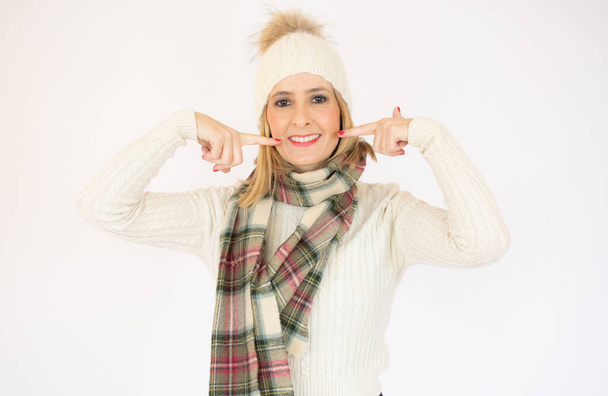 bonita mujer joven en ropa de invierno señalando su boca sobre fondo blanco - Foto, Imagen