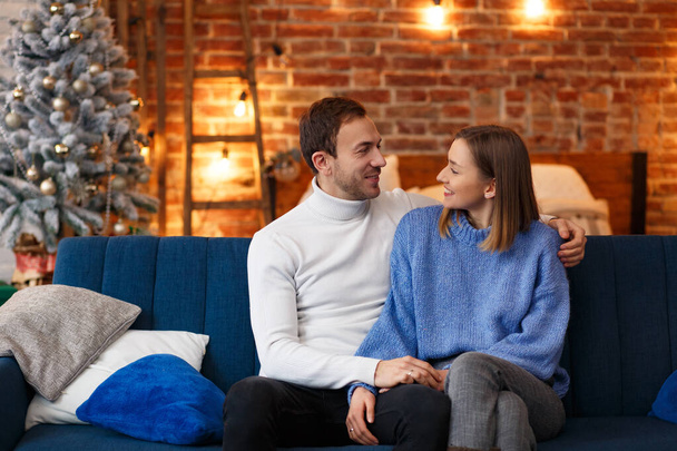 Portrait of beautiful smiling couple hugging at Christmas eve. Beautiful young couple at home enjoying spending time together. Winter holidays, Christmas celebrations, New Year concept - Fotó, kép