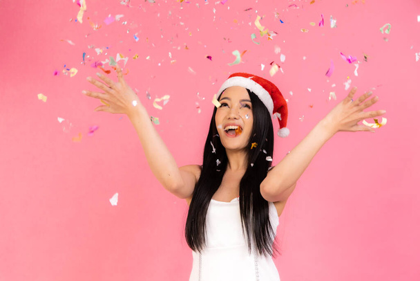 Portrait of two lovely cute asian women in christmas hats  looking at camera isolated over pink background.Attractive asian woman smile in christmas, new year, valentine day, birthday celebration concept. - 写真・画像