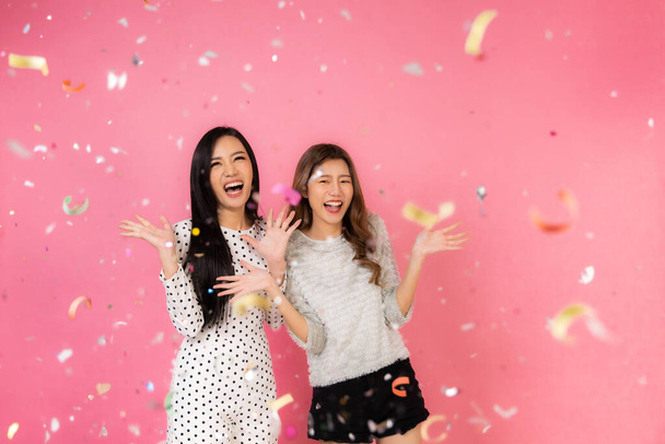 Portrait of two lovely cute asian women in christmas hats  looking at camera isolated over pink background.Attractive asian woman smile in christmas, new year, valentine day, birthday celebration concept. - Foto, imagen