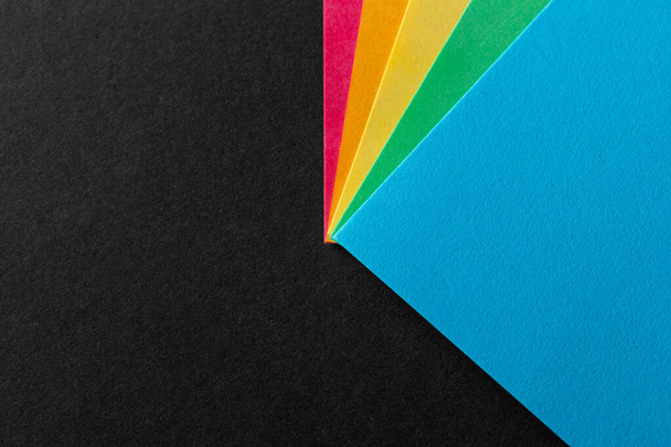 Värilliset sateenkaaren paperikulmat mustalla kuvioidulla taustalla. Liikeidea. Suunnittelun asettelu. Kopioi tila - Valokuva, kuva