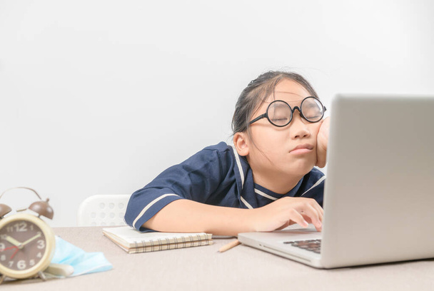 Уставшая студентка в очках спит за столом перед ноутбуком после тяжелого дня учебы онлайн., не осталось энергии, образование и новая нормальная концепция - Фото, изображение