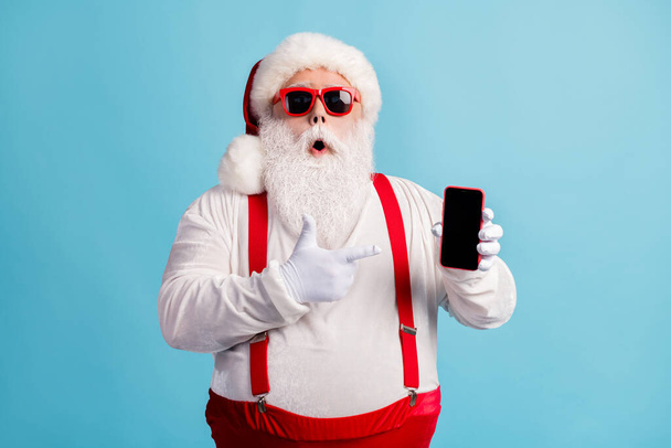 Portrait of his he nice attractive amazed wondered white-haired Santa holding in hand demonstrating device order shop app 5g fast speed isolated bright vivid shine vibrant blue color background - Φωτογραφία, εικόνα
