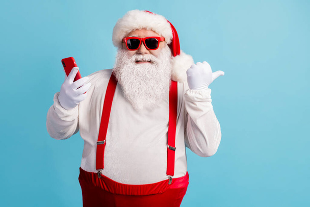 Portrait of his he nice attractive cheerful cheery glad confident white-haired Santa using device demonstrating copy space 5g app isolated bright vivid shine vibrant blue color background - Foto, afbeelding