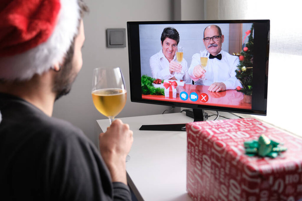 彼らの息子とのビデオ通話でシャンパンでクリスマスの乾杯を祝うシニアカップル.クリスマスお祝いのコンセプト. - 写真・画像