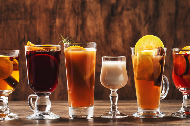 Selection of autumn or winter alcoholic hot drinks and cocktails - mulled wine, glogg, grog, eggnog, warm ginger ale, hot buttered rum, punch, mulled apple cider on wood background, copy space - Zdjęcie, obraz