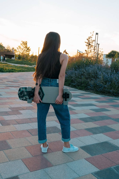 портрет молодої жінки зі скейтбордом на заході сонця
 - Фото, зображення