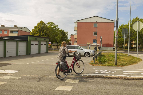 View of woman with bicycle crossing road. Natural city landscape view. Healthy lifestyle. Uppsala. Sweden. 08.20.2020. - Photo, Image